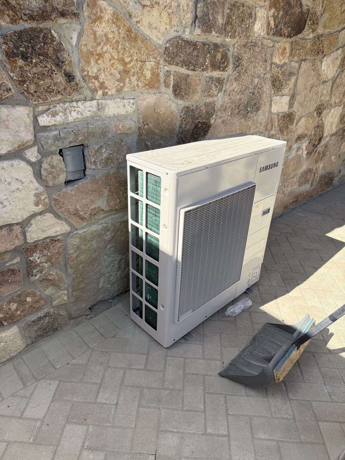 Samsung outdoor mini-split unit freshly installed against a stacked stone wall on a Lehi, Utah home