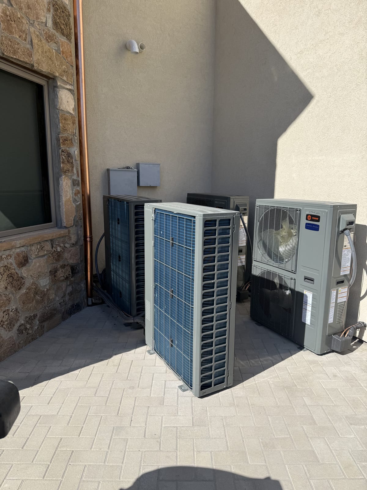 Trane outdoor condenser installed by Monarch Air alongside two existing heat pump units against a Utah home exterior